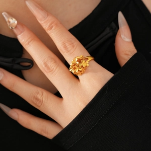 Detailed macro shot of 24k gold plated flower cluster ring on a model's finger