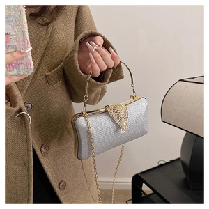 Close-up of silver glitter evening clutch featuring a gold leaf clasp and metal chain