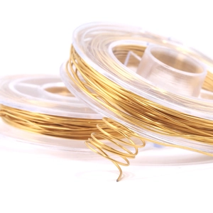 Close-up of golden jewelry wire on transparent spools for DIY crafting and beadwork