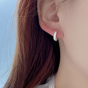 Close-up of minimalist S925 silver earring with white mother-of-pearl worn on earlobe