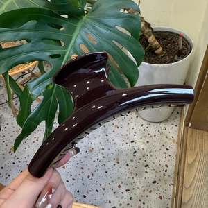 Detail view of a large 15cm glossy dark brown hair claw clip held in hand