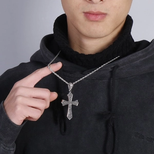 Detail view of retro silver cross pendant with embossed patterns on a twist rope chain