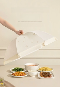 Détail d'une main ouvrant un couvre-plat pliable blanc crème avec maille fine