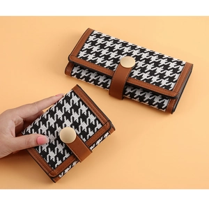 Macro shot of houndstooth long and short wallets with brown leather trim and gold snap buckle