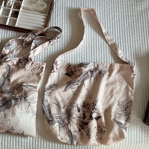 Flat lay of linen tote bags with floral patterns and shoulder straps on white quilted fabric