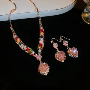 Exquisite gold necklace and earrings set with pink heart zircons on black velvet