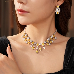 Close-up of elegant floral necklace and drop earrings set with yellow pear-shaped stones