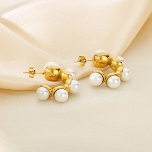 Gros plan de boucles d'oreilles en C en acier doré avec perles blanches sur soie