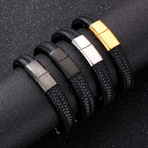 Dettaglio di bracciali in pelle intrecciata da uomo con chiusure in metallo oro, argento e nero