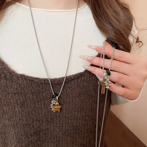 Detail of layered stainless steel necklaces with star and cross stone pendants