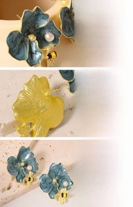 Detailed macro view of blue enamel flower earrings with natural pearls and bee charms