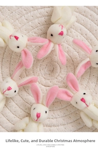 Dettaglio di ciondoli a forma di coniglietto natalizio in peluche bianco con orecchie rosa