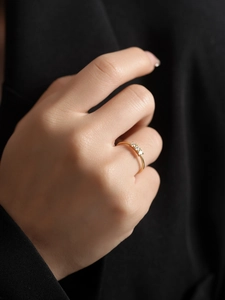 Close-up of minimalist gold plated silver ring featuring three sparkling white zircons