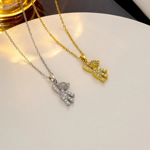 Detail of gold and silver bear necklaces with cubic zirconia on a white pedestal