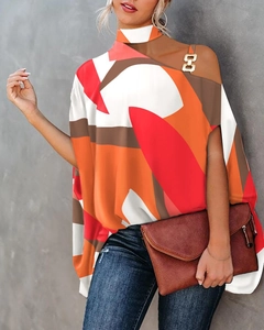 Detail einer bunten Bluse mit geometrischem Print, Neckholder und goldener Metallschnalle