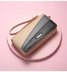 Close-up of a women's long apricot patchwork wallet with dual zippers and wrist strap