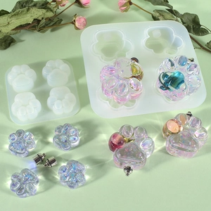 Detail view of silicone molds and finished resin cat paw crafts with holographic glitter