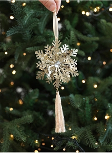 Golden snowflake ornament with center gemstone and silky tassel on a Christmas tree