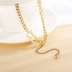 Fashionable gold Cuban link necklace with letter B pendant on a white ceramic plate