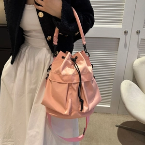 Sac seau rose en nylon avec cordon de serrage porté par un mannequin dans un style épuré