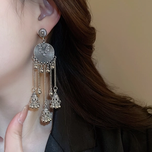 Close-up of vintage silver tassel earrings with ethnic motifs on model side view