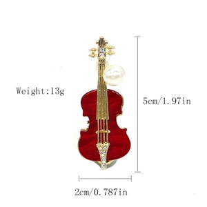 Macro shot of red enamel violin brooch with gold accents and size specifications