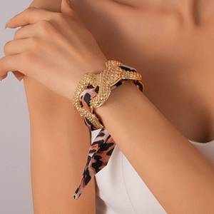 Detail of leopard print ribbon wrapped on textured golden metallic cuff bracelet