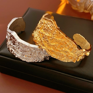 Dettaglio di bracciali dorati e argentati con texture lava su scatola di pelle