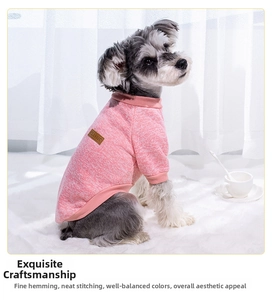 Close-up of pink knit pet sweater with ribbed edges and leather logo on a small dog
