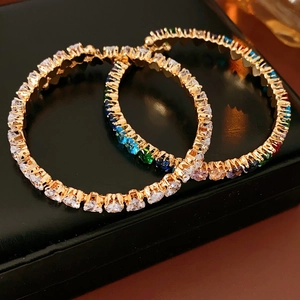 Detail of gold hoop earrings with multi-colored heart-shaped zircon stones