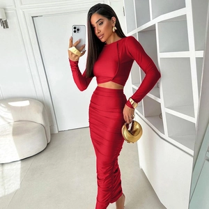 Dettaglio del crop top rosso a maniche lunghe e della gonna lunga arricciata in tessuto lucido
