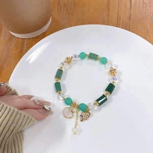 Detail of green beaded bracelet with starfish charms and shells on white plate