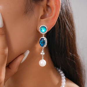 Detail of vintage earrings with blue gemstones, white pearl drops, and crystal pavé