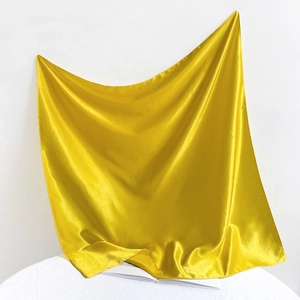 Detail shot of yellow satin fabric with smooth silk texture and glossy folds