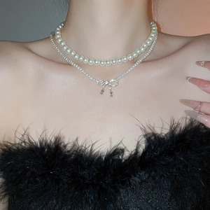 Close-up of double-layer pearl necklace with sparkling zircon bow pendant on neck