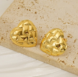 Detailed view of golden quilted heart earrings on a stone and silk background
