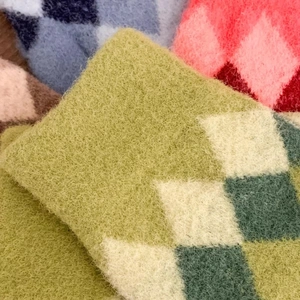 Macro detail of knit fabric texture with argyle patterns in various soft pastel colors