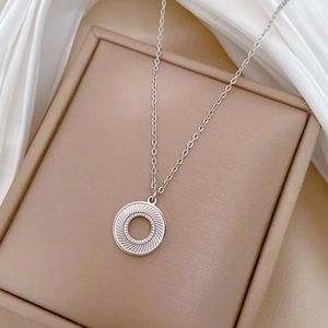 Macro view of a silver rotating circle pendant on a premium silk and jewelry box