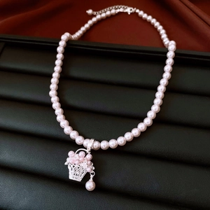 Détail d'un collier de perles avec pendentif panier argenté sur présentoir en cuir