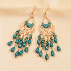 Close-up of bohemian earrings with turquoise beads and golden crescent moon engravings