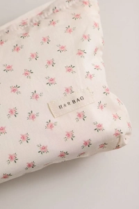 Détail de la trousse de maquillage florale avec motif fleurs roses et étiquette tissée