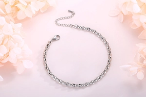 Nahaufnahme einer minimalistischen silbernen Edelstahl-Gliederkette auf rosa Blüten
