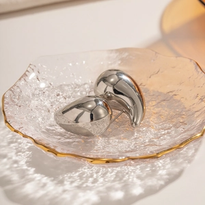 Macro detail of glossy teardrop earrings showing silver polished finish and water-ripple shadows