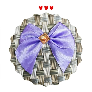 Purple satin bow hair accessory featuring a central amber gemstone with sparkling rhinestones
