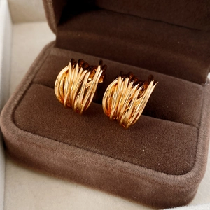 Close-up of gold plated multilayer C-shaped earrings inside a luxury brown velvet jewelry box