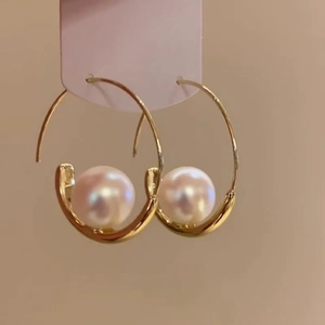Close-up of elegant gold circular hoop earrings with a single white pearl accent