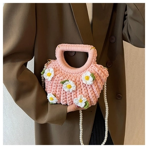Detail of pink hand-woven shell bag with white daisies and an elegant pearl strap