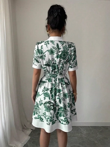 Back view of a white short-sleeved A-line dress with green floral print and waist tie