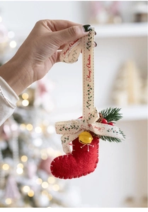 Detail of red felt Christmas stocking ornament with gold bell and green pine branch