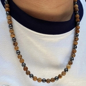 Detailed shot of men's beaded necklace with hematite and tiger eye stones on a white tee